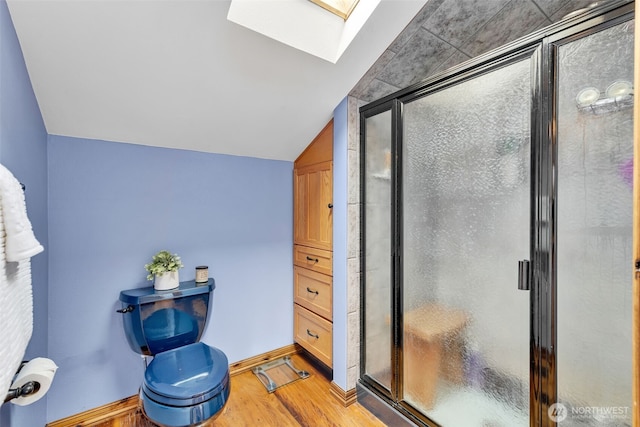 21401 161st Ave E, Graham, WA 98338 - bathroom featuring vaulted ceiling with skylight, a stall shower, baseboards, and wood finished floors