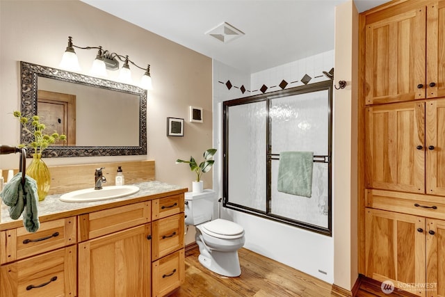 21401 161st Ave E, Graham, WA 98338 - bathroom featuring vanity, wood finished floors, visible vents, shower / bath combination with glass door, and toilet