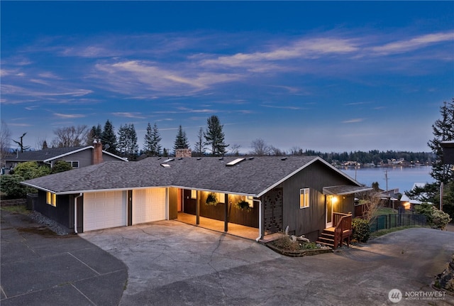 view of front of house featuring a shingled roof, fence, a chimney, a garage, and driveway