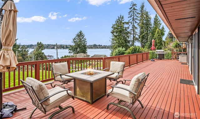 deck featuring grilling area, a fire pit, and a water view