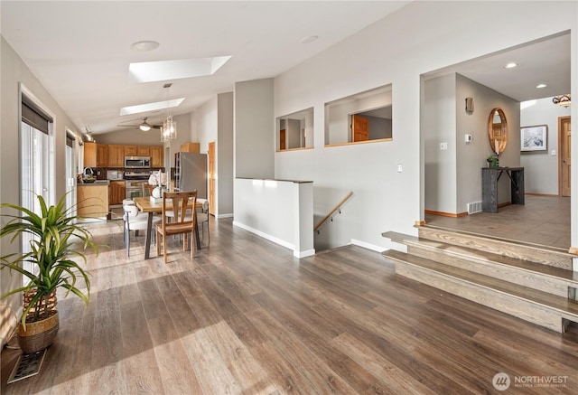 interior space featuring visible vents, wood finished floors, recessed lighting, vaulted ceiling with skylight, and baseboards