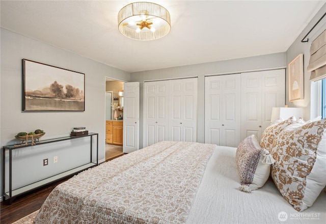 bedroom with dark wood-style floors, connected bathroom, and two closets