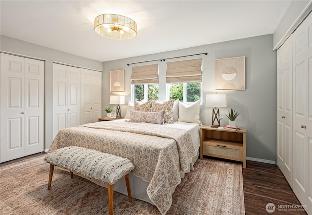 bedroom featuring two closets, baseboards, and wood finished floors