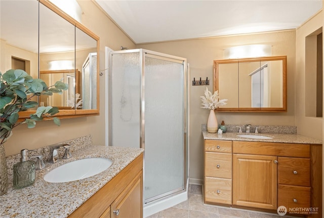 bathroom with a stall shower, two vanities, and a sink