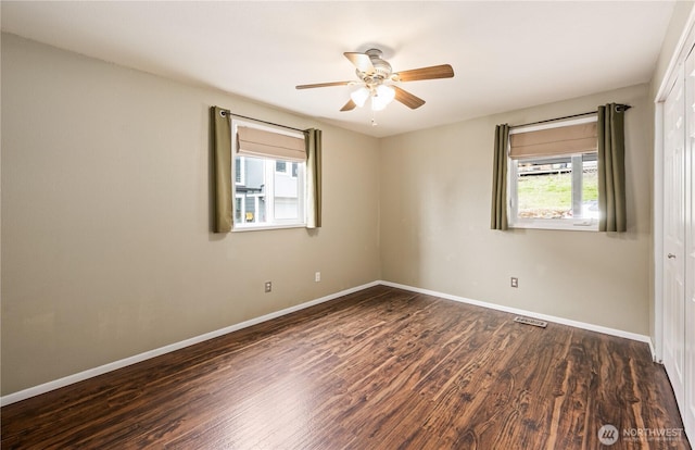 spare room featuring baseboards, wood finished floors, and a ceiling fan