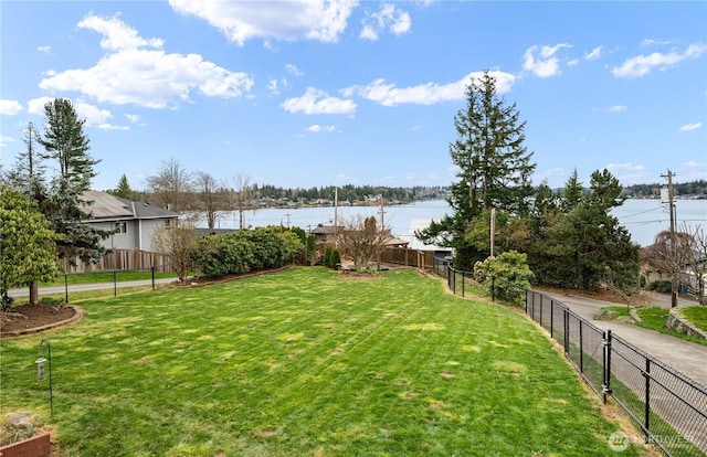 view of yard with a fenced backyard and a water view
