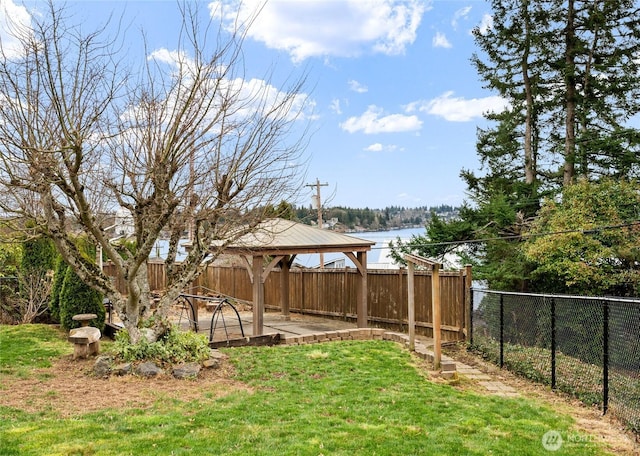 view of yard featuring a gazebo, a deck with water view, and fence