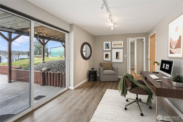 home office featuring rail lighting, light wood-style floors, and baseboards
