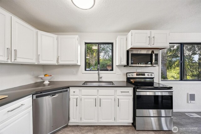 10231 Kiwa Dr SE, Olympia, WA 98513 - kitchen with a sink, dark countertops, white cabinets, visible vents, and appliances with stainless steel finishes