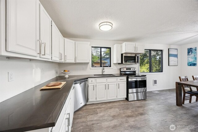 10231 Kiwa Dr SE, Olympia, WA 98513 - kitchen featuring dark countertops, stainless steel appliances, white cabinets, and a textured ceiling