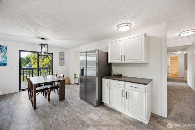 10231 Kiwa Dr SE, Olympia, WA 98513 - kitchen with a textured ceiling, stainless steel refrigerator with ice dispenser, white cabinets, hanging light fixtures, and dark countertops