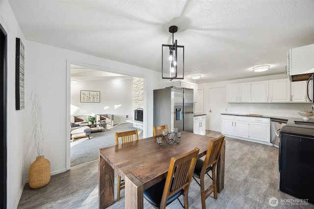 10231 Kiwa Dr SE, Olympia, WA 98513 - dining room featuring a fireplace with raised hearth, light wood finished floors, and a textured ceiling