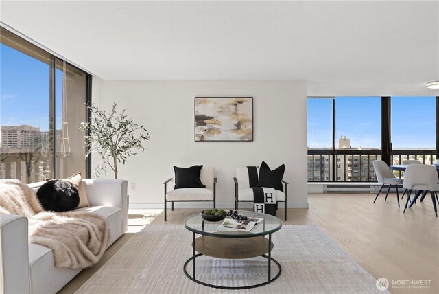 living room featuring expansive windows, baseboard heating, and wood finished floors