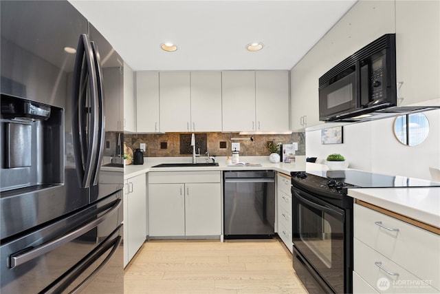 kitchen featuring a sink, light countertops, black appliances, and backsplash