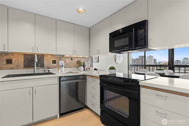 kitchen with light countertops, a sink, black appliances, and a city view