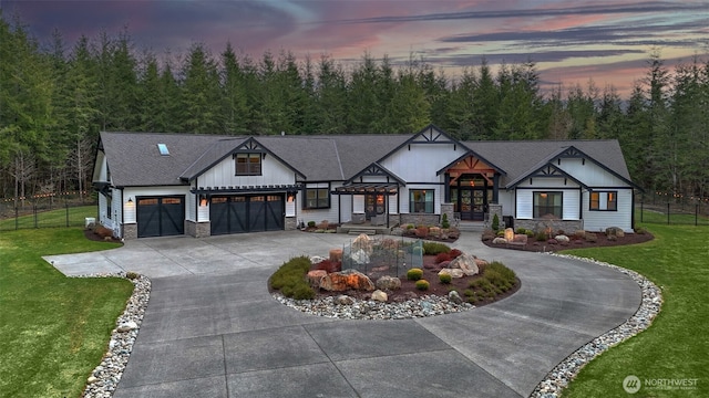 modern farmhouse style home with a lawn, stone siding, curved driveway, fence, and an attached garage