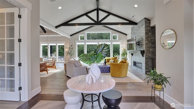 dining space with beamed ceiling, high vaulted ceiling, wood finished floors, and a fireplace