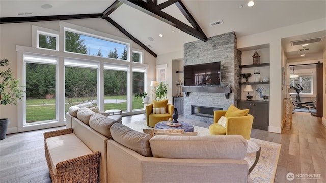 living room with a stone fireplace, high vaulted ceiling, visible vents, and light wood-type flooring