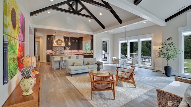 living area with beam ceiling, light wood-style flooring, high vaulted ceiling, and a wealth of natural light