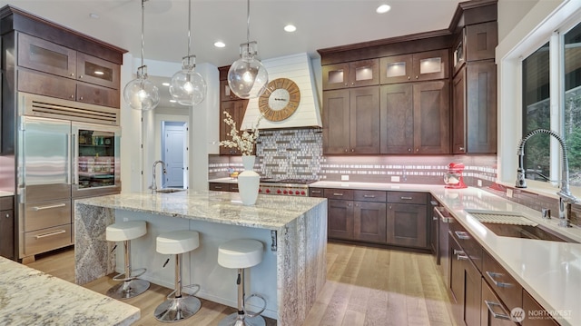 kitchen featuring a sink, stainless steel appliances, light wood-type flooring, and tasteful backsplash