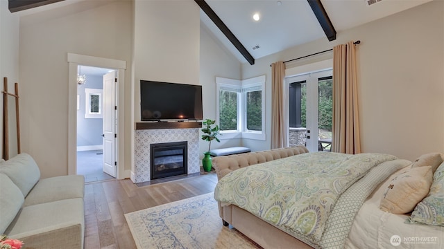 bedroom featuring wood finished floors, high vaulted ceiling, a tile fireplace, access to exterior, and beamed ceiling