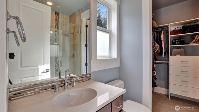 full bathroom with vanity, a spacious closet, toilet, and a stall shower