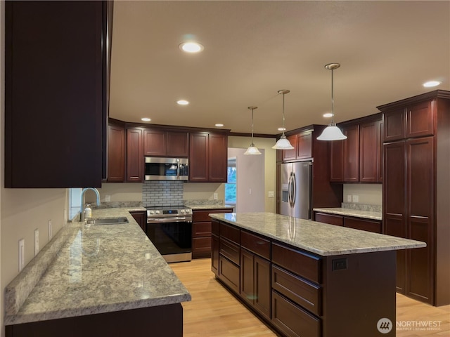 kitchen with light wood-style flooring, stainless steel appliances, recessed lighting, a kitchen island, and a sink