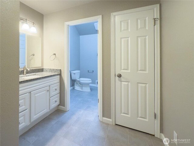 bathroom featuring baseboards, toilet, tile patterned flooring, and vanity