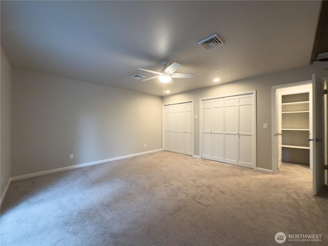 unfurnished bedroom featuring baseboards, visible vents, multiple closets, and carpet