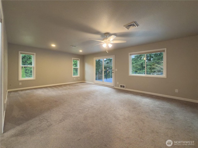 carpeted spare room with baseboards, visible vents, and a ceiling fan