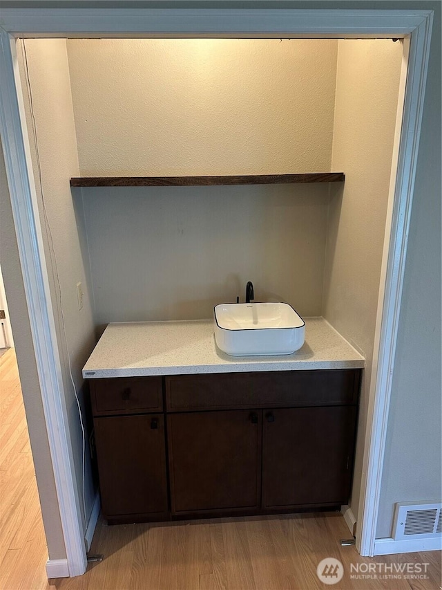 bathroom with visible vents, vanity, and wood finished floors