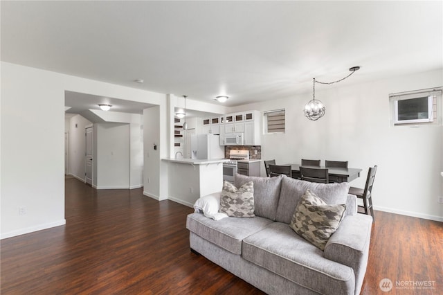 living area with an inviting chandelier, baseboards, and dark wood finished floors