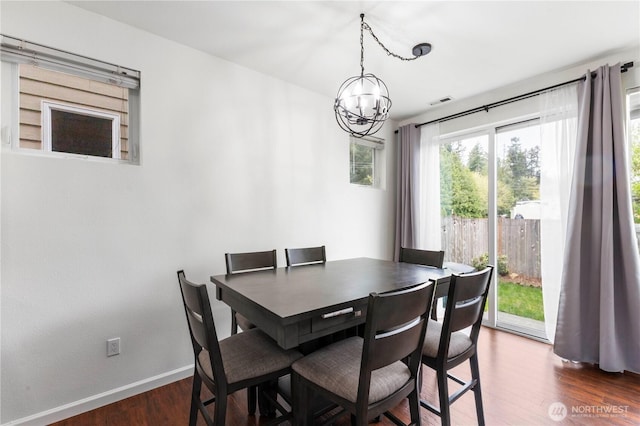 dining area featuring baseboards, visible vents, dark wood-type flooring, and a chandelier
