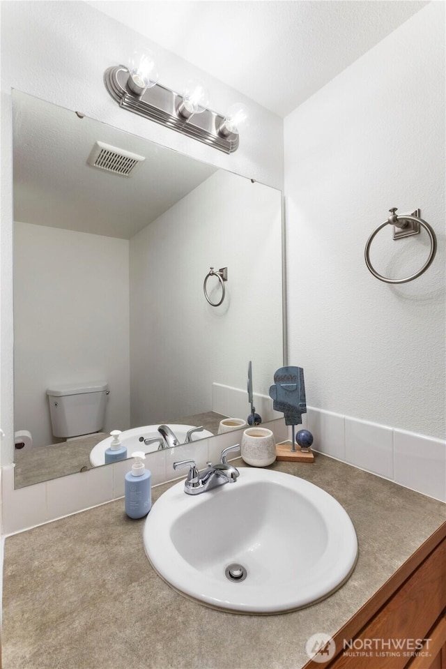 bathroom featuring toilet, visible vents, and vanity