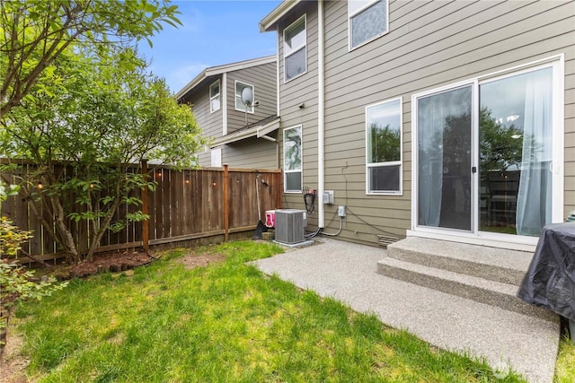 rear view of property with a lawn, central AC unit, fence, and entry steps