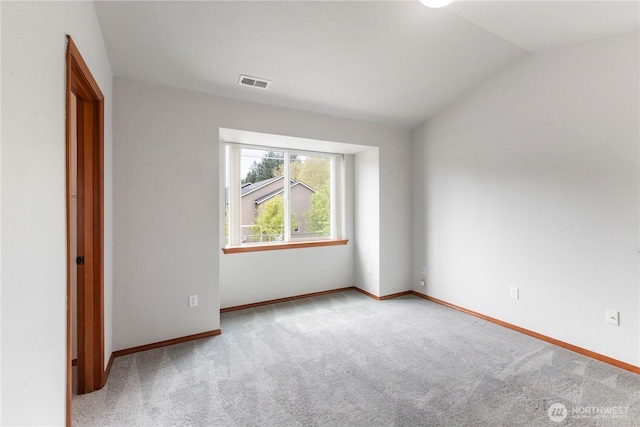 carpeted empty room featuring baseboards, lofted ceiling, and visible vents