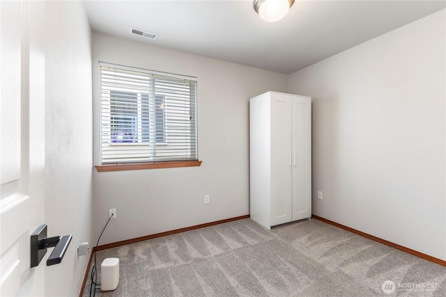 unfurnished bedroom featuring baseboards, light carpet, and visible vents