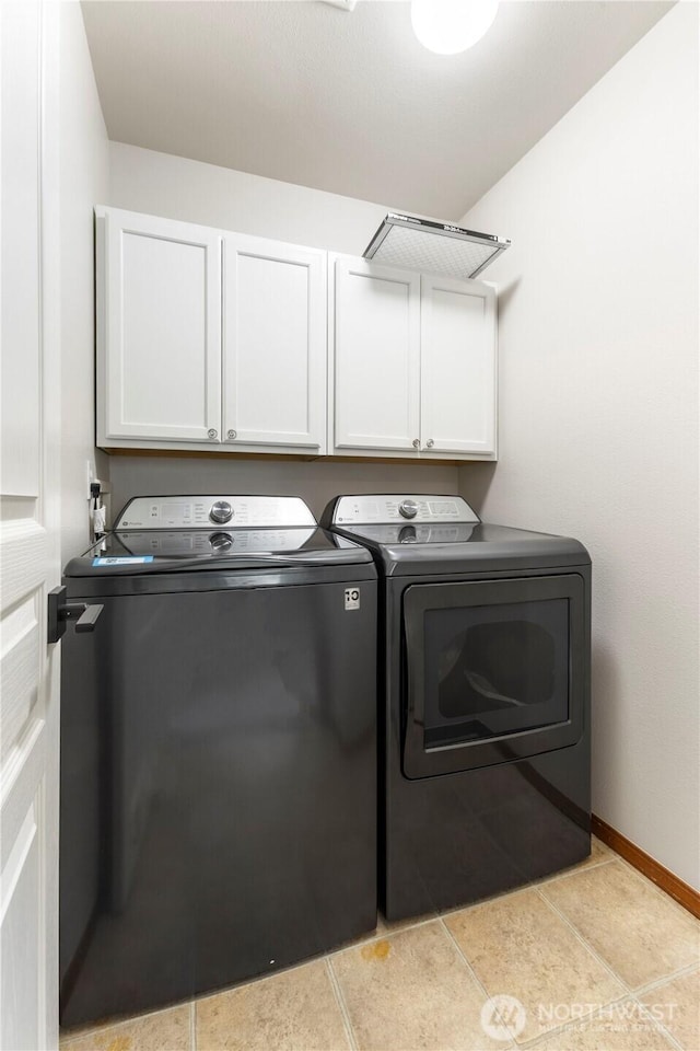 laundry area featuring light tile patterned floors, baseboards, washing machine and dryer, and cabinet space
