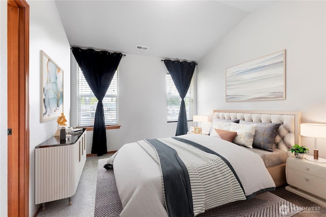 carpeted bedroom with visible vents and vaulted ceiling