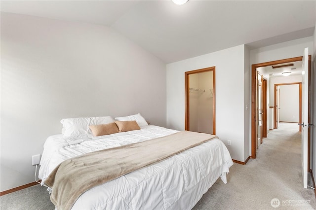 bedroom with baseboards, vaulted ceiling, light carpet, and a spacious closet