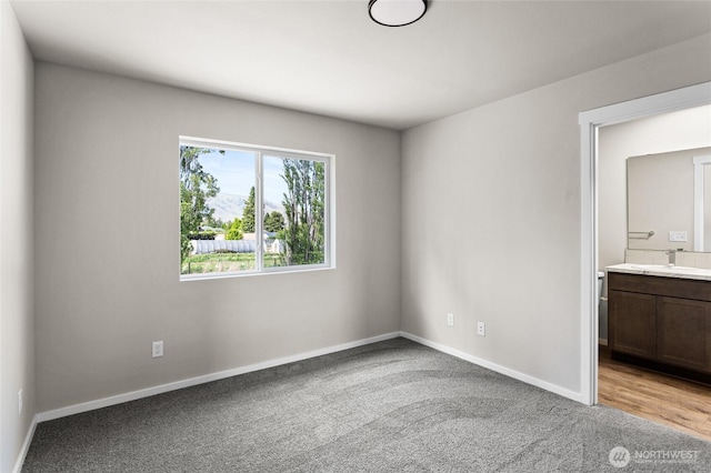 425 Pear Dr, Tieton, WA 98947 - unfurnished bedroom featuring baseboards, ensuite bath, a sink, and light colored carpet