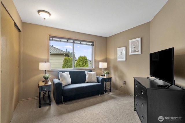 living area with baseboards and light colored carpet