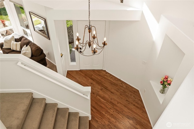 stairway featuring a chandelier, wood finished floors, and baseboards