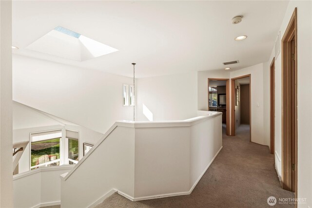 hall with carpet flooring, visible vents, recessed lighting, an upstairs landing, and a skylight