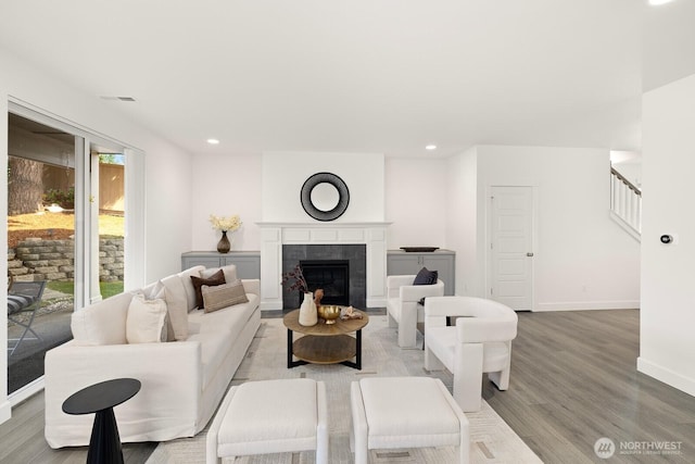 living area with stairs, recessed lighting, baseboards, a fireplace, and wood finished floors