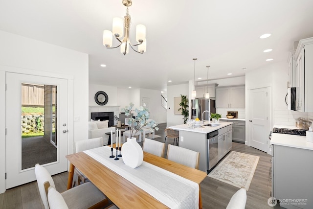 dining room featuring a fireplace, wood finished floors, recessed lighting, and an inviting chandelier