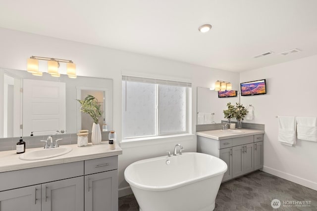 bathroom featuring visible vents, a sink, and two vanities