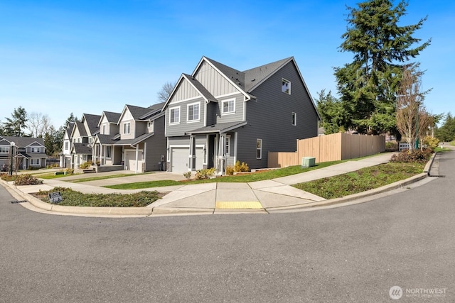 view of front of home featuring concrete driveway, fence, an attached garage, board and batten siding, and a residential view