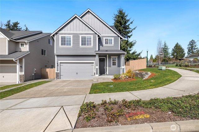 view of front of home featuring stone siding, fence, a garage, board and batten siding, and driveway