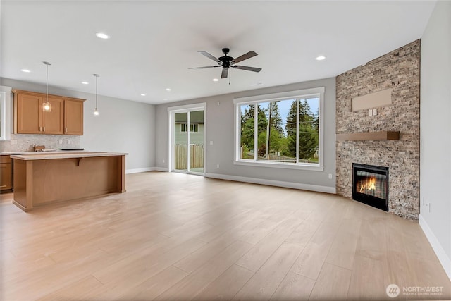 17318 74th Avenue Ct E, Puyallup, WA 98375 - unfurnished living room with a ceiling fan, light wood finished floors, recessed lighting, a stone fireplace, and baseboards